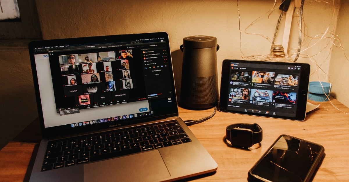 Laptop and tablet on a desk with video conference software open showing multiple parties